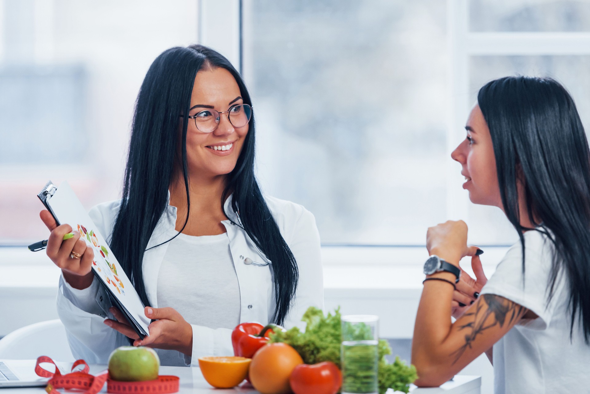 Female nutritionist gives consultation to patient indoors in the office by using notepad